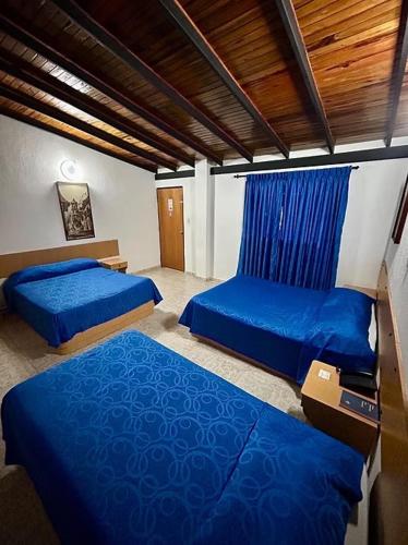 two beds in a room with blue sheets at Oviedo Hotel R in Mérida
