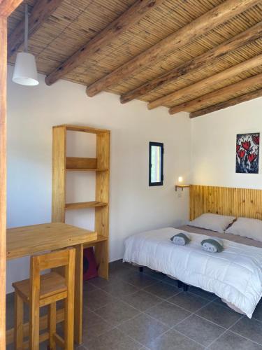a bedroom with a bed and a wooden desk at cabañas UMA RAYMI in Juella