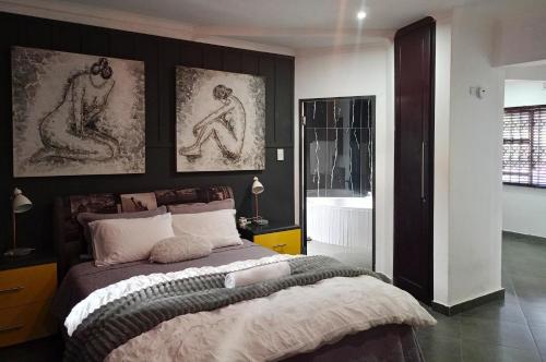 a bedroom with a bed and two paintings on the wall at Vanilla Lee Guest House in Richards Bay