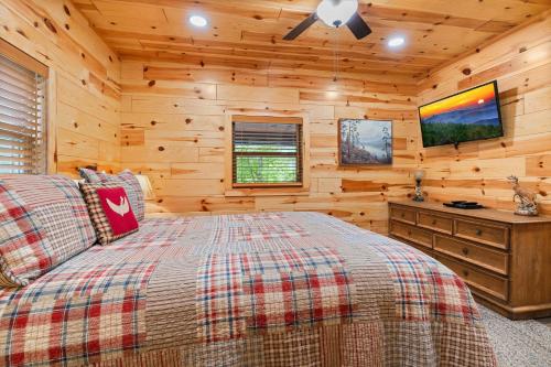a bedroom with a bed and a tv in a log cabin at Beside Still Water 2 in Cosby