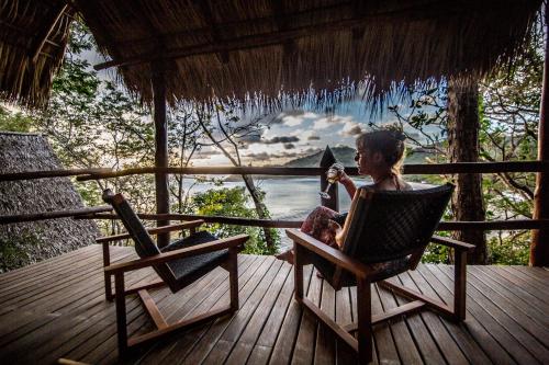 a woman sitting in a chair on a deck at Morgan's Rock in San Juan del Sur