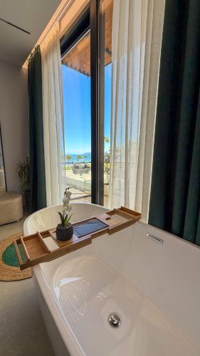 a bathroom with a bath tub with a large window at TreA Suites By Aria in Vlorë