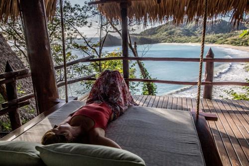 a person laying on a hammock on a porch at Morgan's Rock in San Juan del Sur