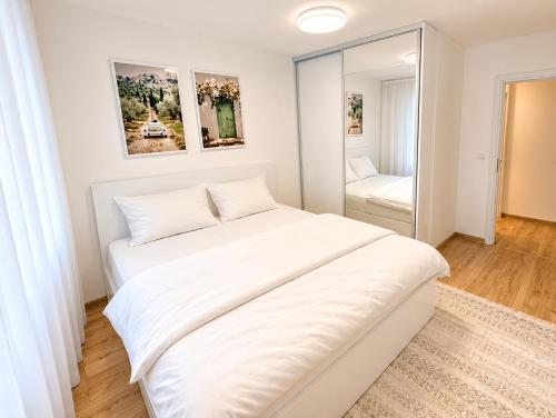 a white bedroom with a large bed and a mirror at Sara Luxe Family in Konjic