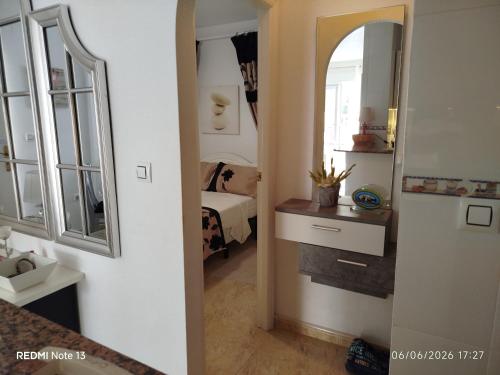 a hallway leading to a bedroom with a bed and a mirror at location appartement isla plana espagne in Isla Plana
