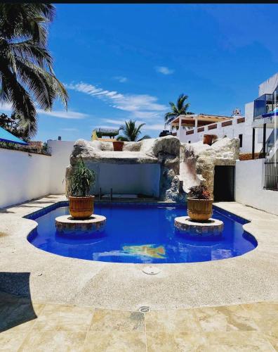 a large blue pool with two potted plants in a courtyard at Mar Real Suites Guayabitos in Rincon de Guayabitos