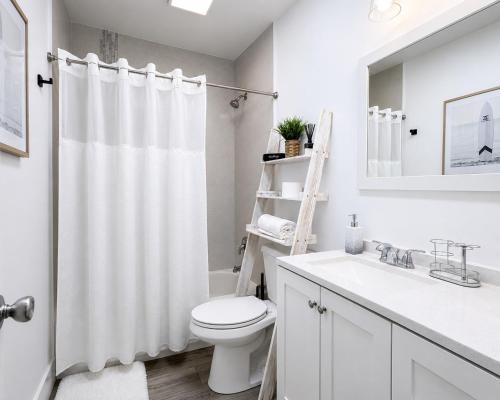 a white bathroom with a toilet and a sink at Tropical Oasis 3 Bedroom House with Hot Tub West Palm Beach in West Palm Beach