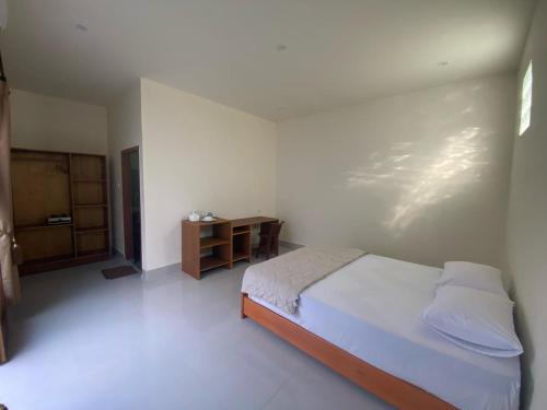 a white bedroom with a bed and a table at Datang Kemari Bungalow in Gili Islands