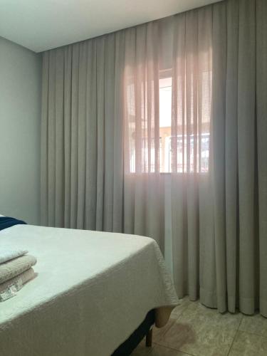 a bedroom with a bed and a window with curtains at Casa completa e confortável in Leopoldina