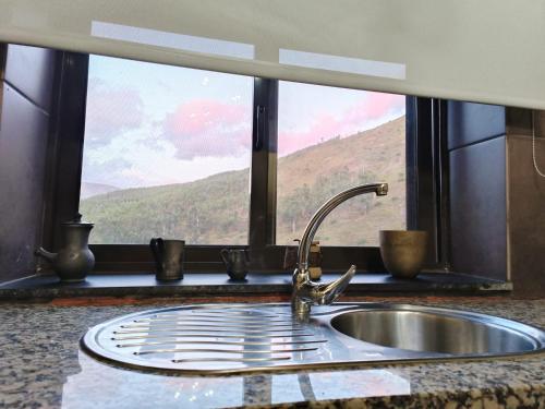a kitchen sink in front of a window with a view at Casa dos avós 23 in Castro Daire
