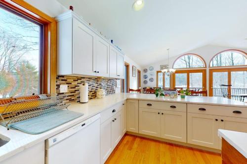 a kitchen with white cabinets and a large window at Ski Bike the East in Stowe