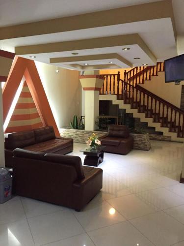 una gran sala de estar con sofás y una escalera. en Hotel Faraon en Tacna