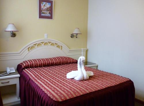 a white stuffed animal sitting on top of a bed at Hotel Faraon in Tacna