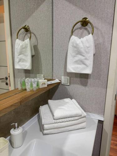 a bathroom with a sink and a mirror and towels at Sheraton Apartments in Bishkek