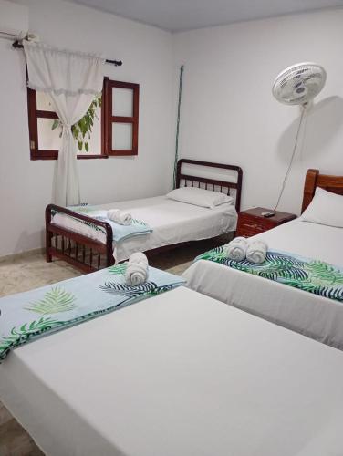 a room with three beds and a fan at Casa Hotel Bijaos in Mompós