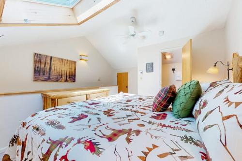 a bedroom with a bed with a comforter and pillows at Nordic Wilderness Lodge in Bartlett