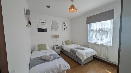 a bedroom with two beds and a window at CJ Maison - "Spacious Family Friendly 2-Bedroom Apartment in the City Centre with free on-site parking, free Wi-Fi" in Southampton