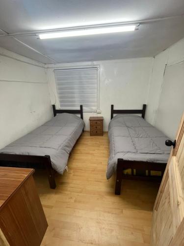two beds in a small room with a window at Habitación Hostal Refugio Gaucho in Cochrane