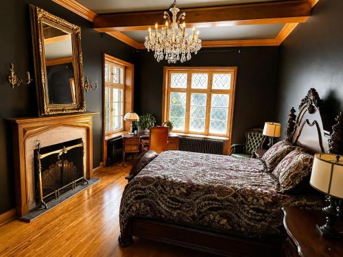 a bedroom with a bed and a fireplace and a chandelier at Winston Churchill - le charme Tudor au cœur de Sherbrooke in Sherbrooke