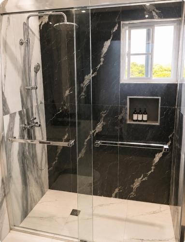 a bathroom with a shower with a glass door at Glenmuir La Ville - Gated Com May Pen in May Pen