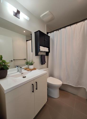a white bathroom with a toilet and a sink at The Alpine City Escape in Calgary