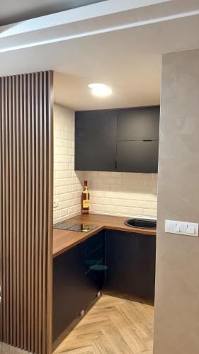 a kitchen with a wooden counter top and black cabinets at Villa NOA in Bijeljina