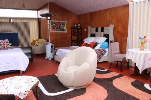 a bedroom with a bed and a white chair at Titicaca Wara wara Lodge in Puno