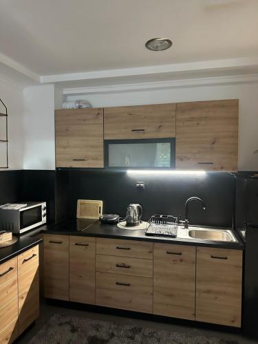 a kitchen with wooden cabinets and a sink at Monteluce Apartment Vlašić in Šišava