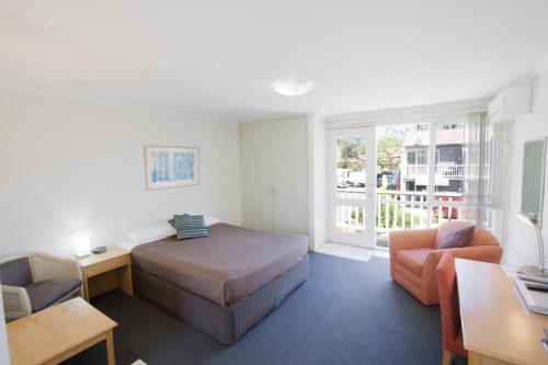 a bedroom with a bed and a desk and a chair at Summer East Apartments in Orange