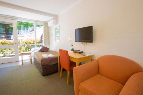 a living room with a couch and a table and a tv at Summer East Apartments in Orange