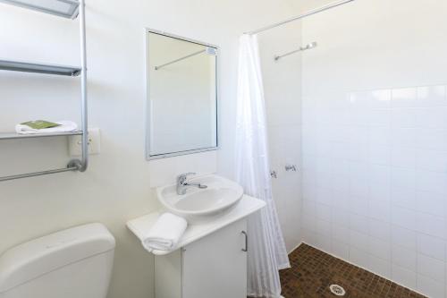 a white bathroom with a toilet and a sink at Summer East Apartments in Orange