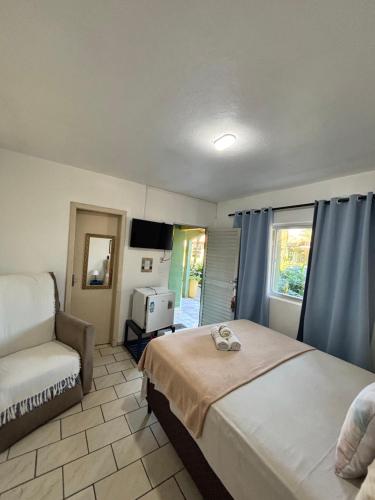 a bedroom with a bed and a couch and a window at Pousada Anturio in Barra Velha