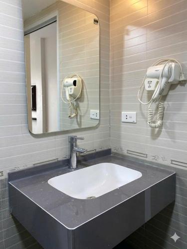 a bathroom sink with a mirror and a hair dryer at Valoria Premium Hanoi Hotel and Travel in Hanoi