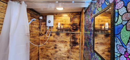 a bathroom with a shower with a wooden wall at Sameer Mountain View Retreat in Tanah Rata