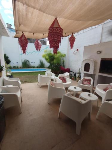 a patio with white couches and tables and a fireplace at Güemes Hostel Cordoba in Córdoba