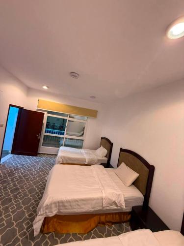 two beds in a room with a window at استراحة الرايس in Rayyis