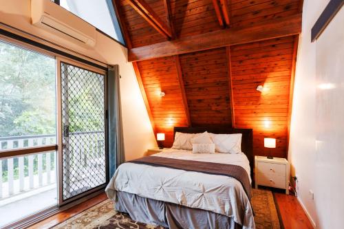 a bedroom with a bed and a large window at Family & Friends Cottage in Mount Tamborine