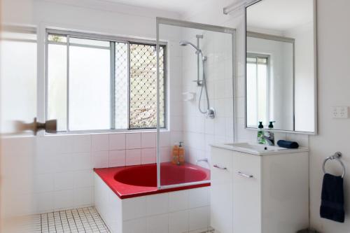 a bathroom with a red tub and a red sink at Family & Friends Cottage in Mount Tamborine