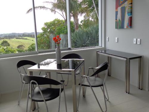 a dining room with a table and chairs and a window at The Nikau Loft in Onetangi
