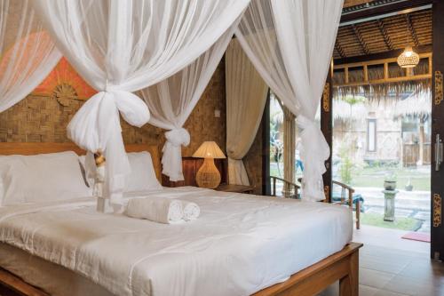 a bedroom with a bed with white drapes at Pondok Sapta Sallaca in Selat