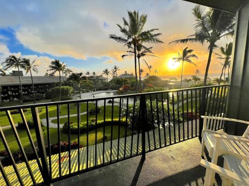 a balcony with a view of palm trees and the sunset at Oceanview Studio at Kauai Beach Resort #2444 in Lihue