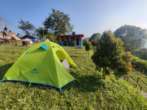 a green tent sitting in the grass near a house at Thursina Camping Ground in Paragajen