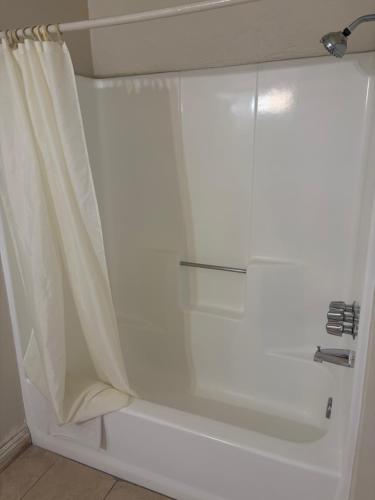 a shower with a glass door with a shower curtain at Townhouse Motel- Alhambra-South Pasadena-San Marino in Alhambra