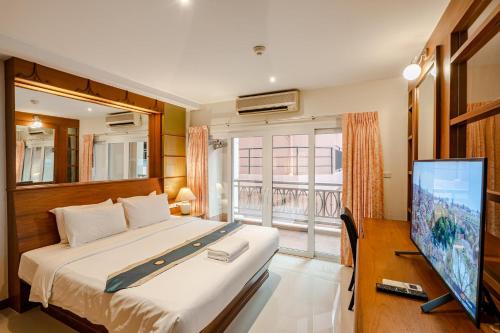a bedroom with a bed and a flat screen tv at Whitehouse Condotel in Pattaya