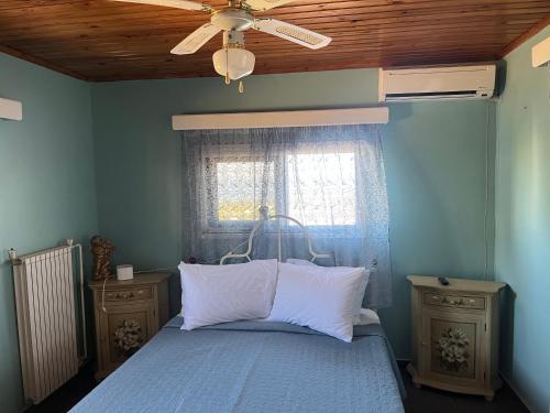 a bedroom with a bed with a ceiling fan and a window at Krista's house in Agioi Theodoroi