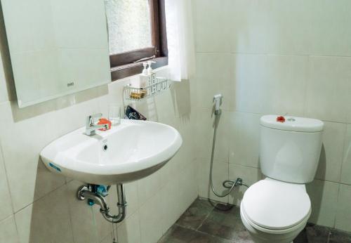 a white bathroom with a toilet and a sink at Pondok Sapta Sallaca in Selat