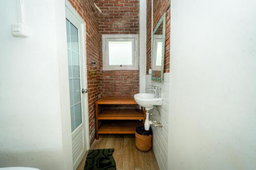 a bathroom with a sink and a brick wall at Wisma Nirwana Tretes near Cimory Prigen in Prigen