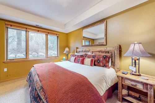 a bedroom with a bed and a table with a lamp at Evergreen Retreat, Unit 101 in Avon