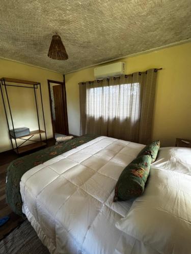 a large white bed in a bedroom with a window at Chalé Retiro Real in Ouro Preto