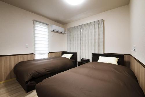 a bedroom with two beds and a window at 萩別邸 シーサイド1 HAGI Bettei SEASIDE1 in Hagi